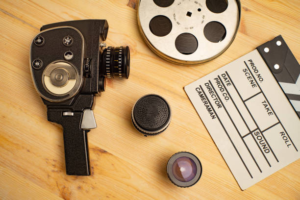 Movie clapper, film reel and camera on wooden background, top view